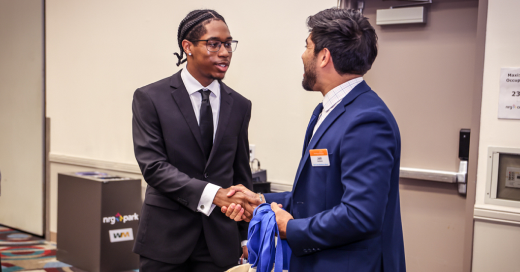 A Workforce Solutions staff member shakes hands with a job seeker in a conference room, smiling warmly.