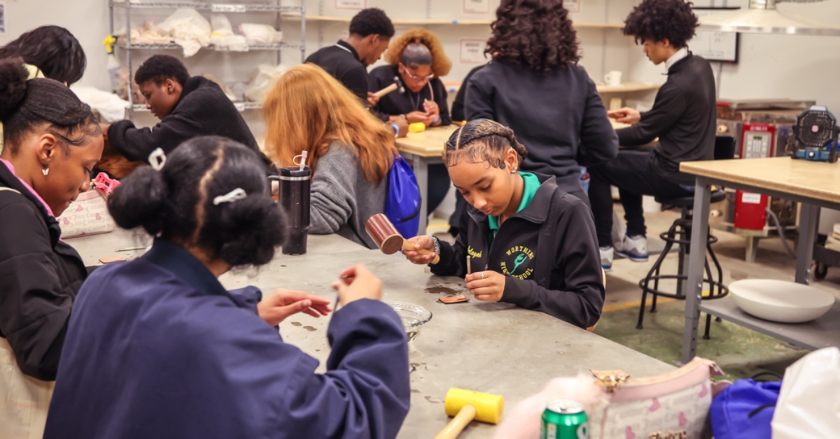A group of students in a workshop, focused on crafting projects at a table.