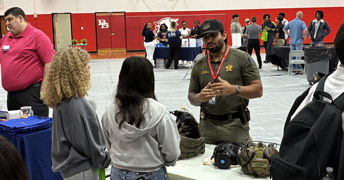 Bellville High School Hiring event Two high school students engage with a law enforcement officer at a Hiring Event in Bellville High School.
