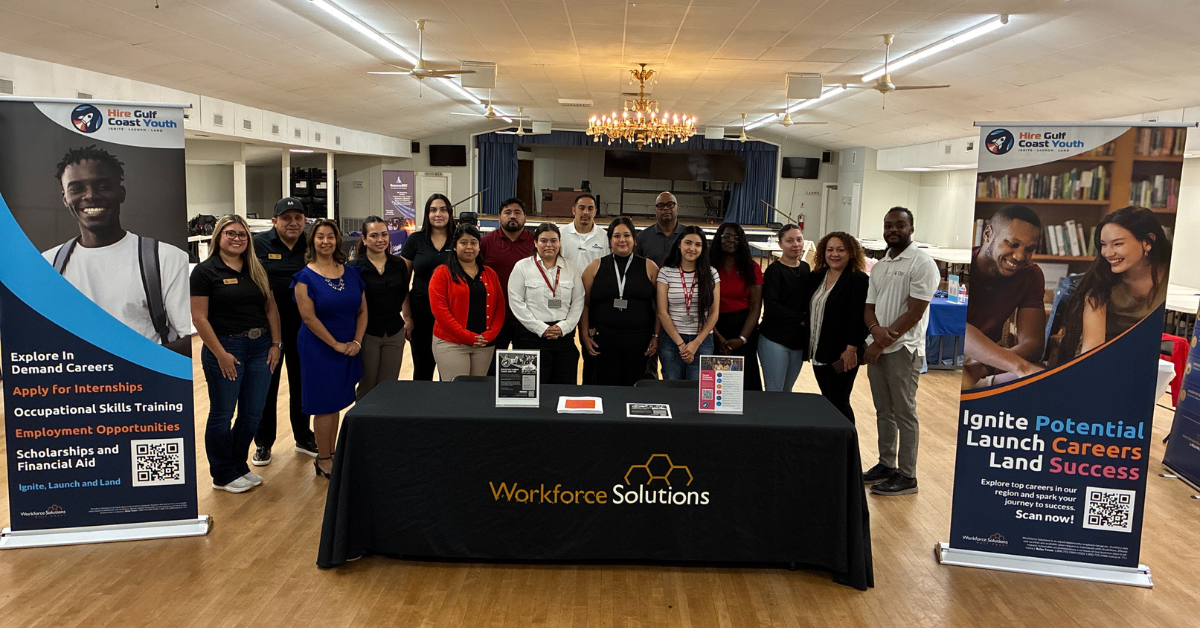 A group of people stands behind a table with a "Workforce Solutions" banner at the HGCY American Legion Job Fair.