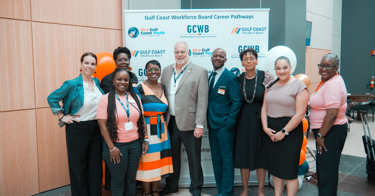 Texas Gulf Coast Workforce Summit A diverse group of nine people smiling at a Gulf Coast Workforce Board event at the Education Summit.
