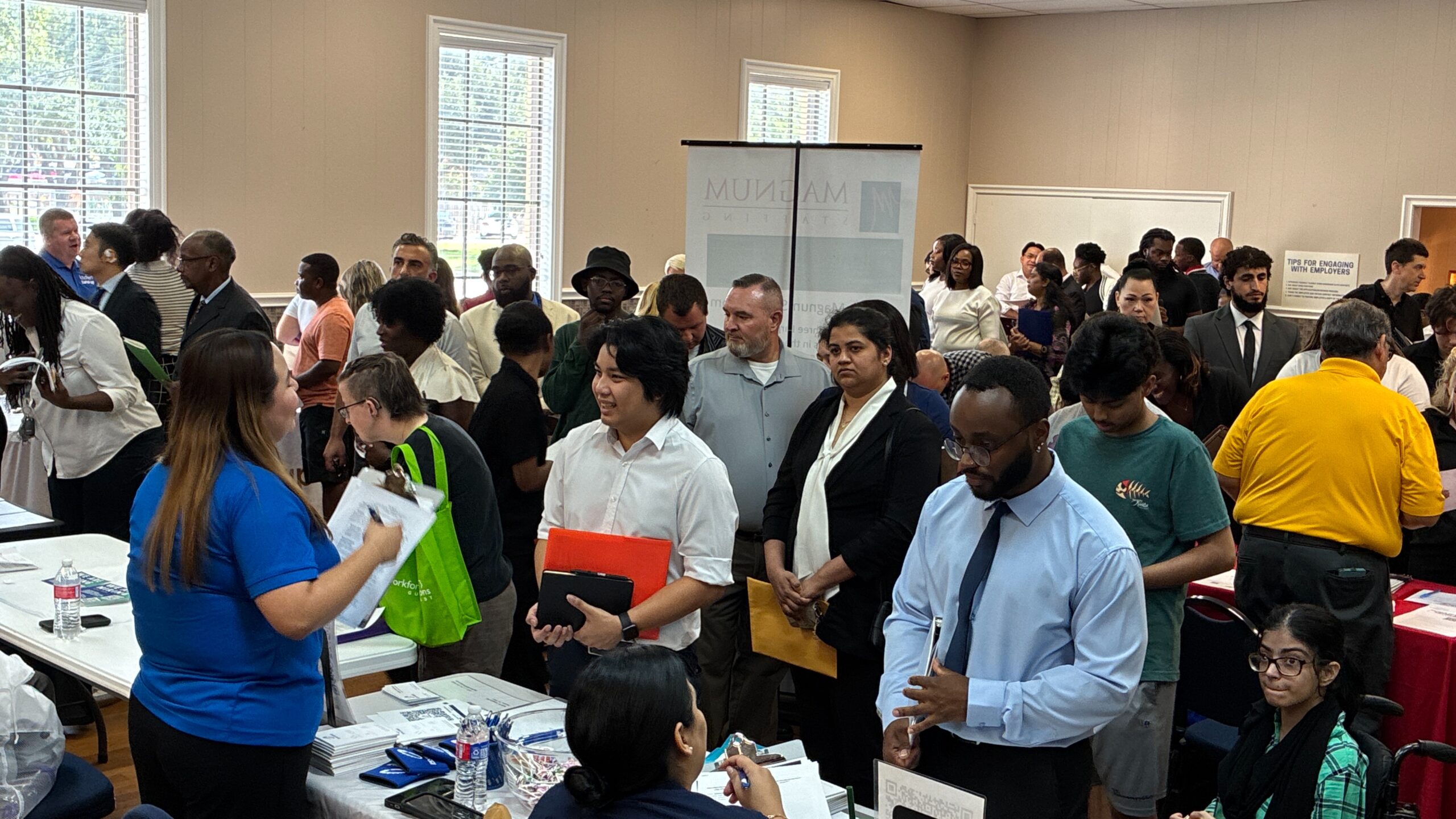 Community Job Fair Job seekers speak with employer representatives at a crowded community hiring and career fair.