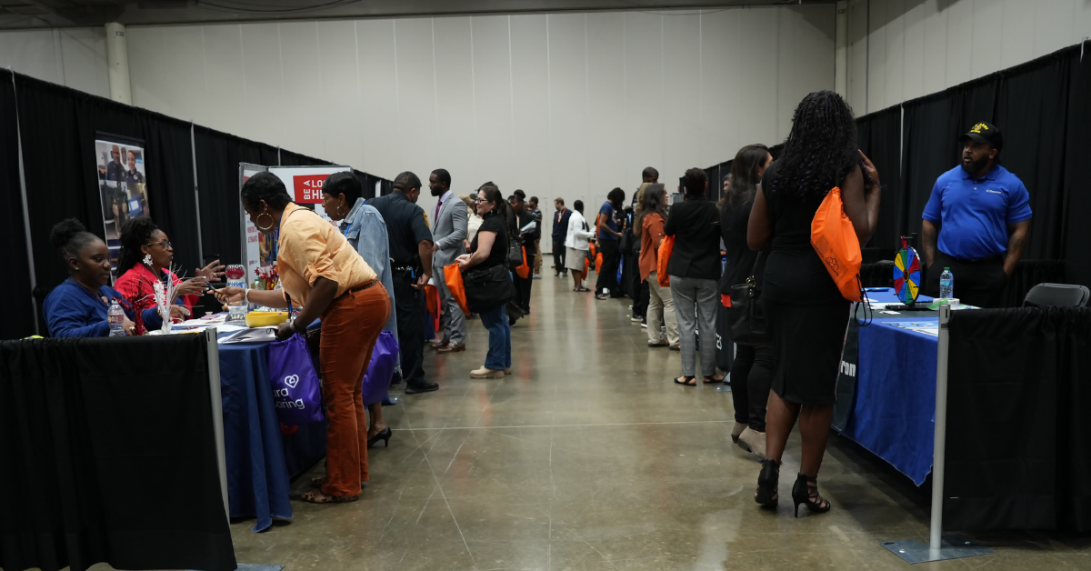 Community members visit employer and resource booths during a career fair inside a convention hall.