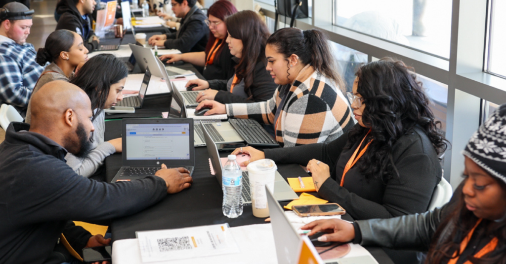 Workforce staff assisting job seekers on laptops during a career support and employment services event.