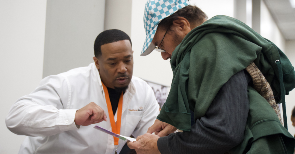 Workforce Solutions Gulf Coast representative assisting an attendee with information during a community workforce event.